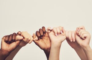 Cropped shot of a group of unrecognizable people holding one another's thumbs in a single line